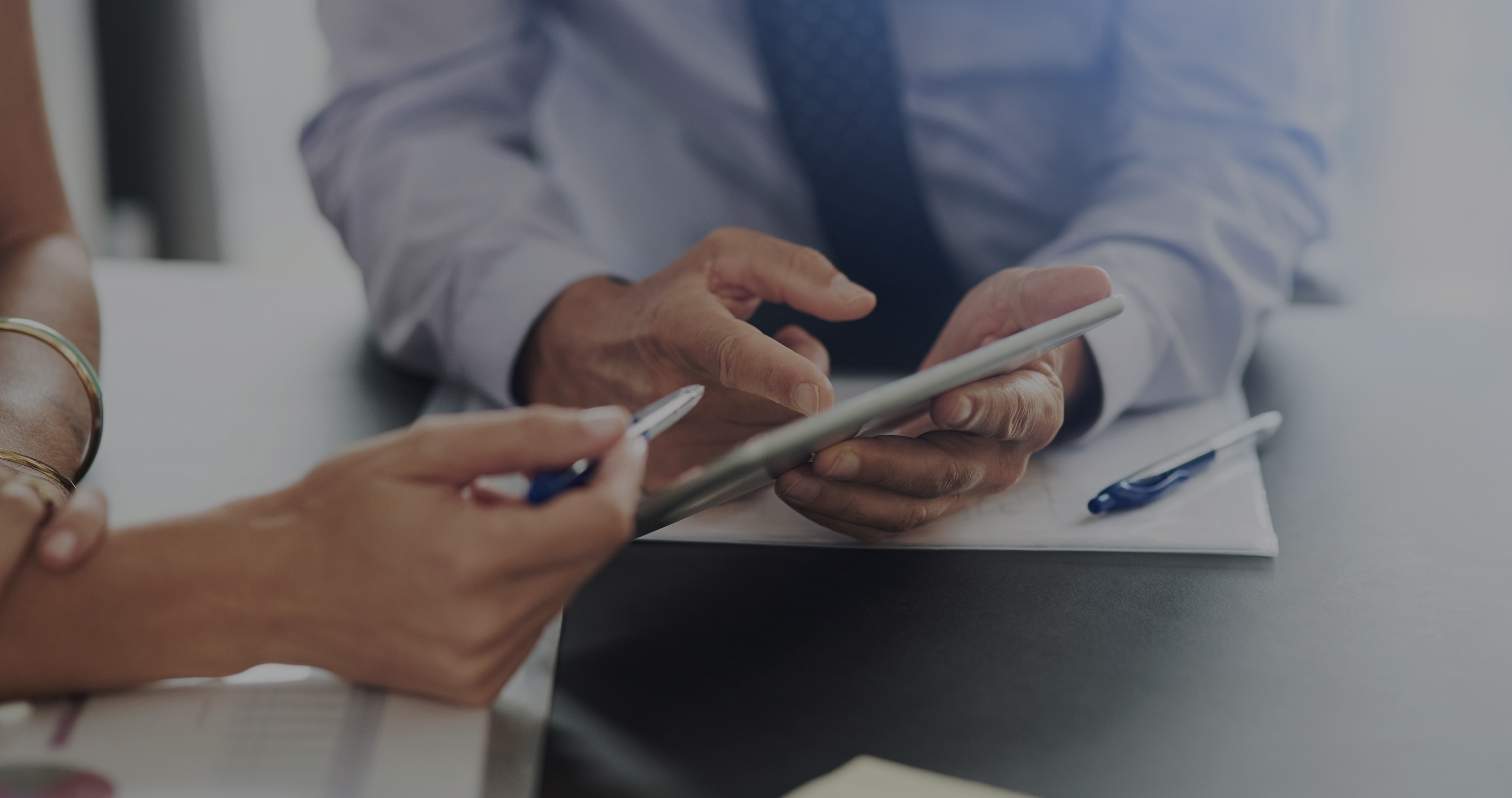 Two people reviewing loan details on a tablet during a business meeting